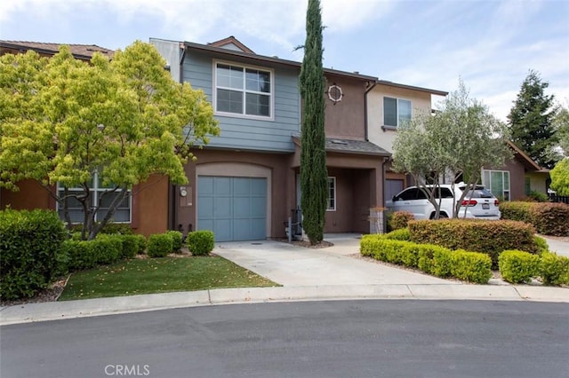 multi unit property with an attached garage, driveway, and stucco siding