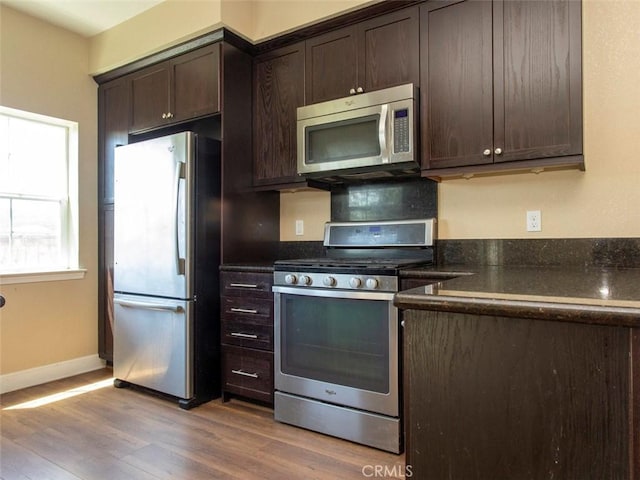 kitchen featuring appliances with stainless steel finishes, baseboards, wood finished floors, and dark brown cabinets