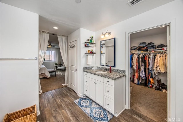 full bath with vanity, ceiling fan, wood finished floors, and visible vents