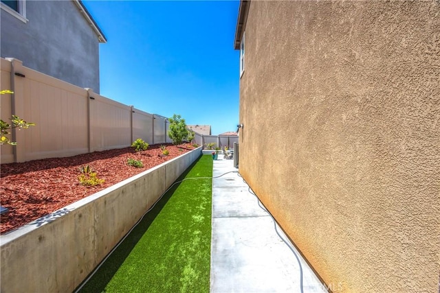 view of side of home with stucco siding and fence