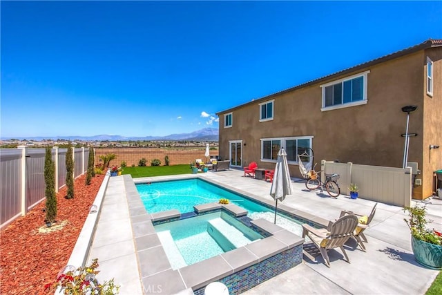 view of pool featuring a pool with connected hot tub, a mountain view, a fenced backyard, and a patio area