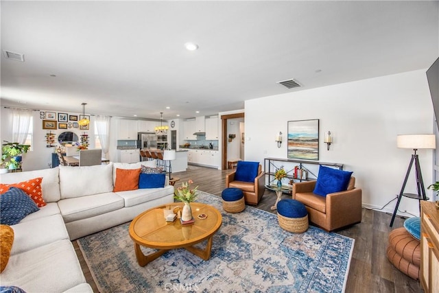 living area with recessed lighting, visible vents, and dark wood-style floors