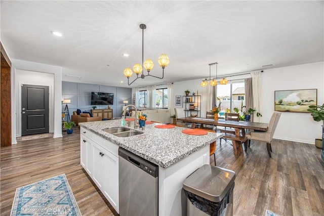 kitchen featuring stainless steel dishwasher, a sink, open floor plan, an inviting chandelier, and white cabinetry