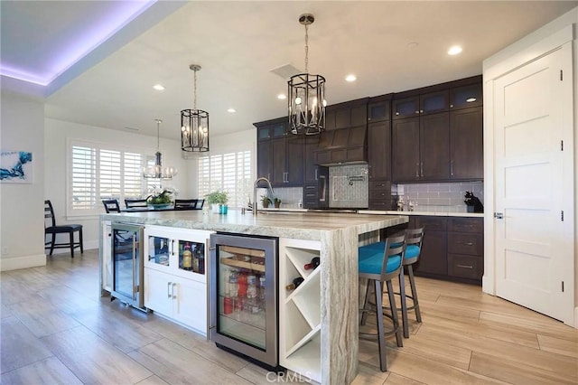 kitchen featuring dark brown cabinetry, beverage cooler, and a chandelier