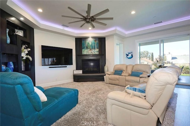 living room featuring ceiling fan, visible vents, a raised ceiling, baseboards, and recessed lighting