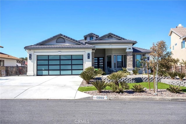 view of front of property featuring concrete driveway, an attached garage, fence, and stucco siding