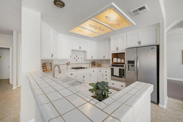 1366 Via Cibola, Oceanside, CA 92057 - kitchen with tile countertops, visible vents, appliances with stainless steel finishes, a sink, and a peninsula