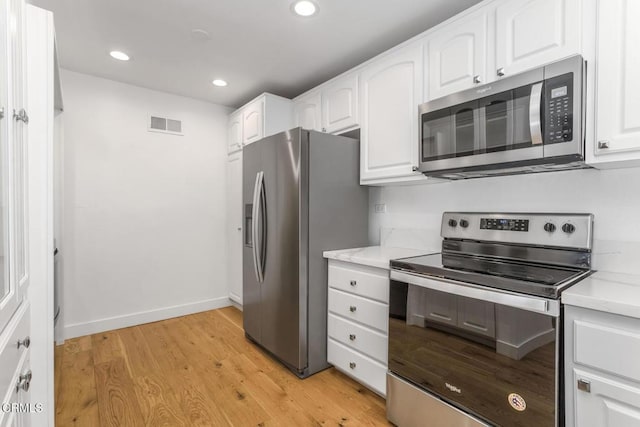 kitchen with light wood-style floors, stainless steel appliances, white cabinetry, and visible vents
