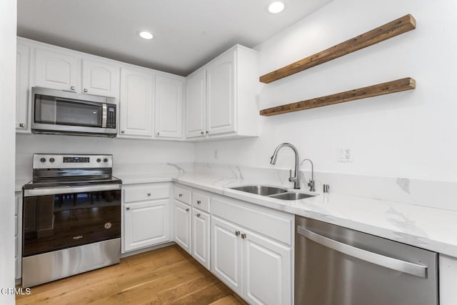 kitchen featuring open shelves, a sink, light stone counters, stainless steel appliances, and white cabinetry