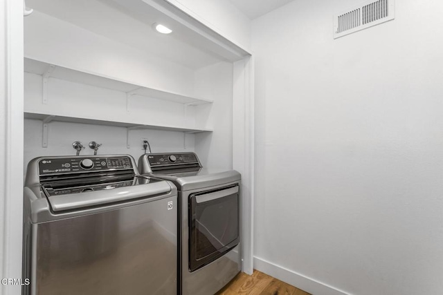 laundry area with laundry area, visible vents, light wood-type flooring, baseboards, and washer and dryer