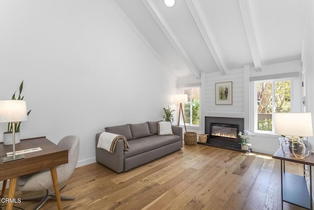 living room featuring a glass covered fireplace, vaulted ceiling with beams, and wood finished floors