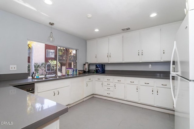 kitchen with dark countertops, a sink, freestanding refrigerator, recessed lighting, and visible vents