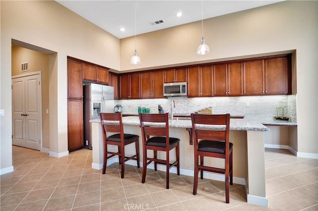 kitchen with hanging light fixtures, tasteful backsplash, stainless steel appliances, and light tile patterned flooring