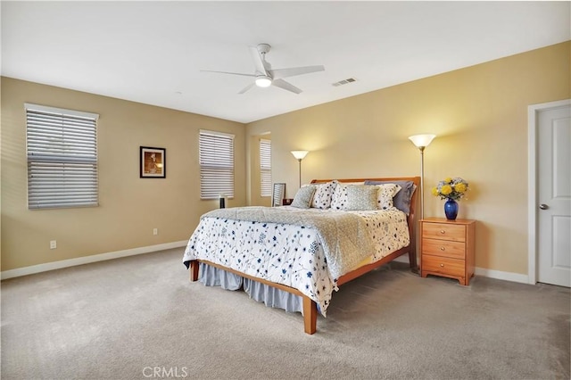 carpeted bedroom with baseboards, visible vents, multiple windows, and ceiling fan