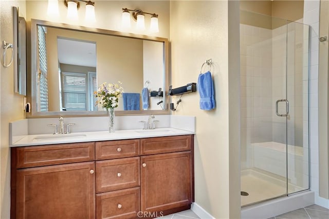 full bathroom with double vanity, a sink, tile patterned floors, and a shower stall