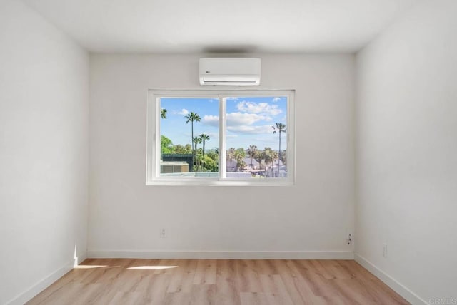 empty room with baseboards, a wall unit AC, and light wood-style flooring