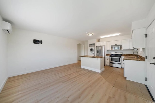 kitchen featuring dark countertops, a sink, arched walkways, stainless steel appliances, and stacked washer / dryer