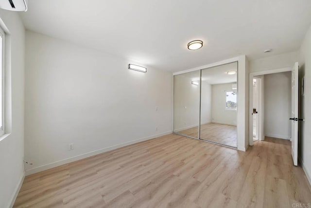 unfurnished bedroom with light wood-style floors, baseboards, and a closet