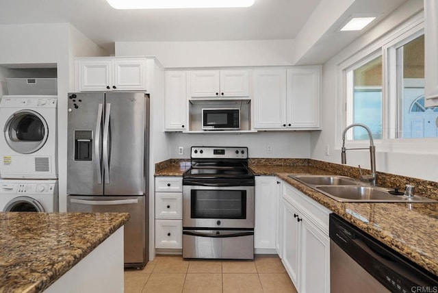 kitchen featuring a sink, white cabinets, appliances with stainless steel finishes, and stacked washer / dryer