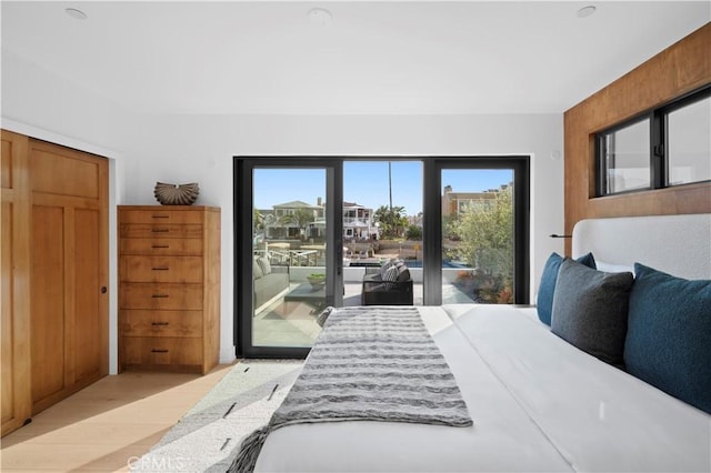 bedroom featuring access to exterior, light wood-style flooring, and multiple windows