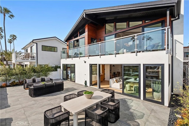 back of property featuring an outdoor living space, stucco siding, a balcony, and a patio