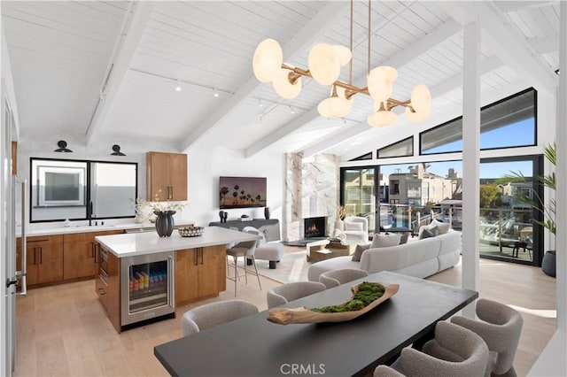 dining room with plenty of natural light, light wood-type flooring, beverage cooler, and a notable chandelier