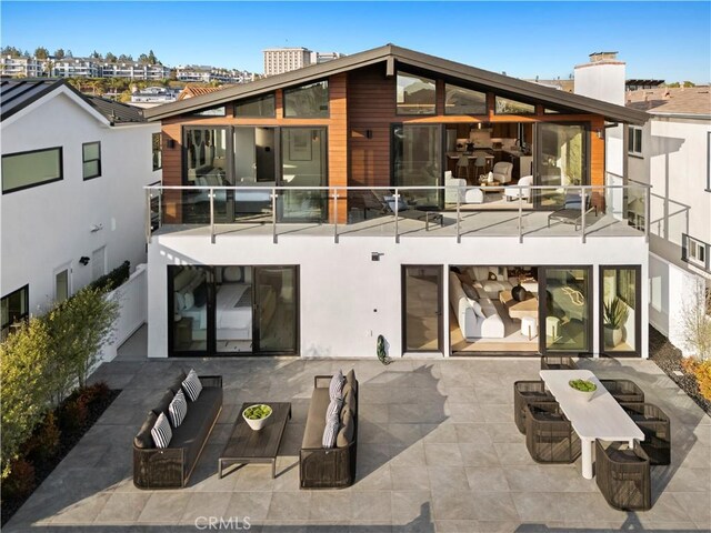 rear view of property with a patio, an outdoor living space, a balcony, and a chimney