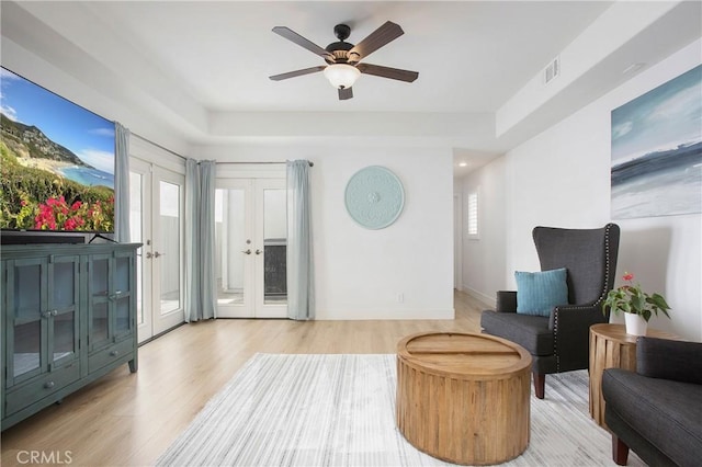 living area featuring visible vents, plenty of natural light, light wood finished floors, and ceiling fan
