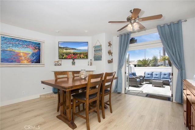 dining area featuring baseboards, ceiling fan, and light wood finished floors