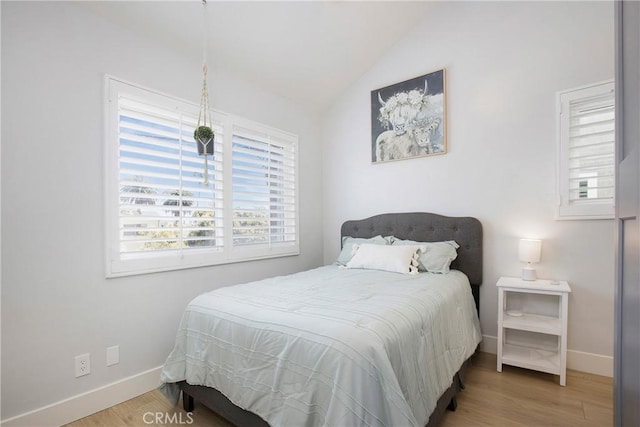 bedroom featuring baseboards, lofted ceiling, and wood finished floors