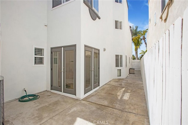 rear view of house featuring a fenced backyard, stucco siding, a patio area, and french doors