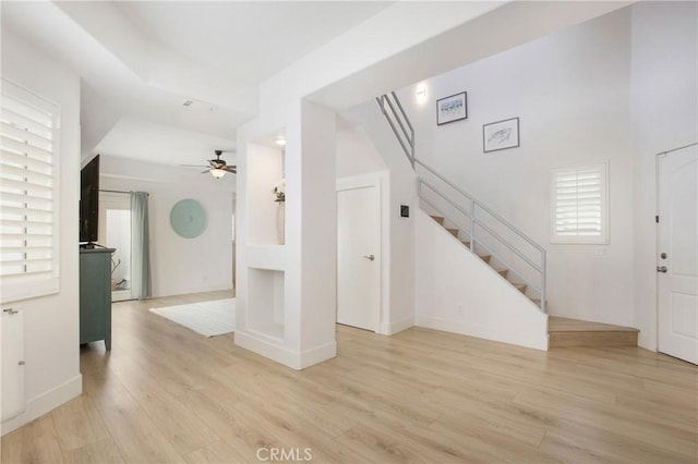entrance foyer featuring stairway, baseboards, light wood-style floors, and a ceiling fan