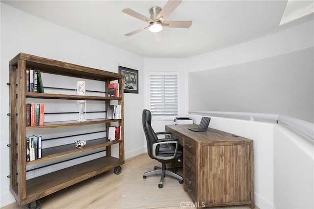 home office featuring light wood-style floors, a ceiling fan, and baseboards