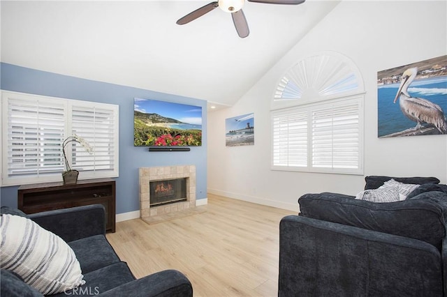living area featuring baseboards, ceiling fan, wood finished floors, and a fireplace