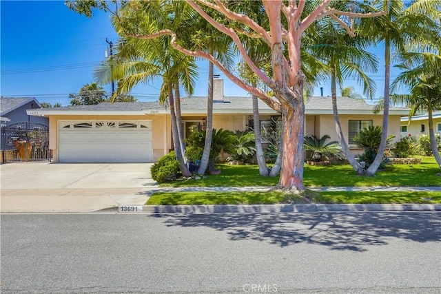 view of front facade featuring stucco siding, an attached garage, driveway, and a front yard