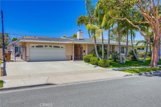 view of front of home with stucco siding, a chimney, a gate, an attached garage, and driveway