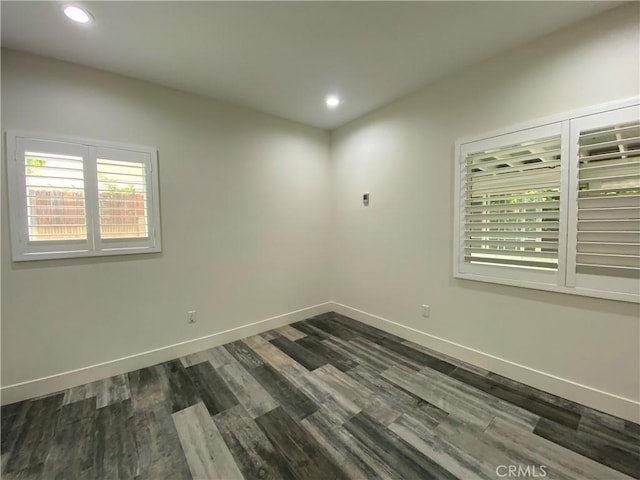 spare room featuring recessed lighting, baseboards, and dark wood-type flooring