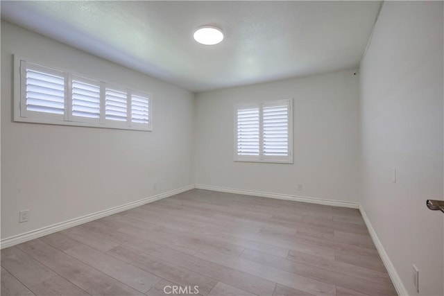 empty room with baseboards, plenty of natural light, and wood finished floors