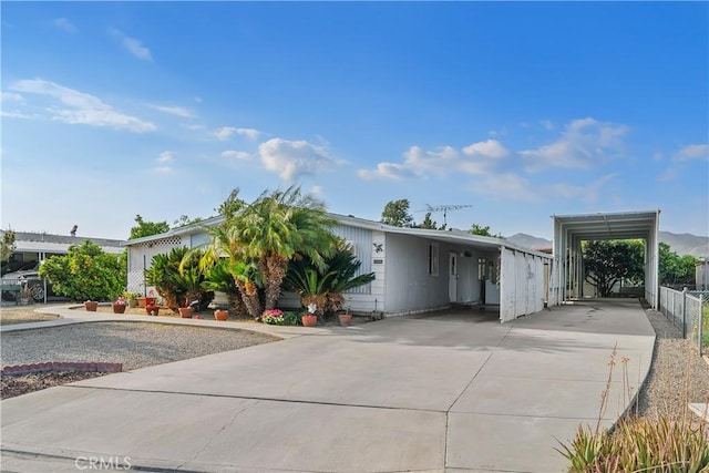 view of front of property featuring fence, an attached carport, and concrete driveway