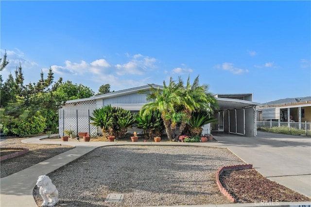 manufactured / mobile home featuring fence, driveway, and a carport