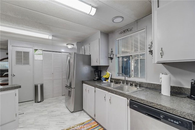 kitchen featuring visible vents, appliances with stainless steel finishes, dark countertops, a sink, and marble finish floor
