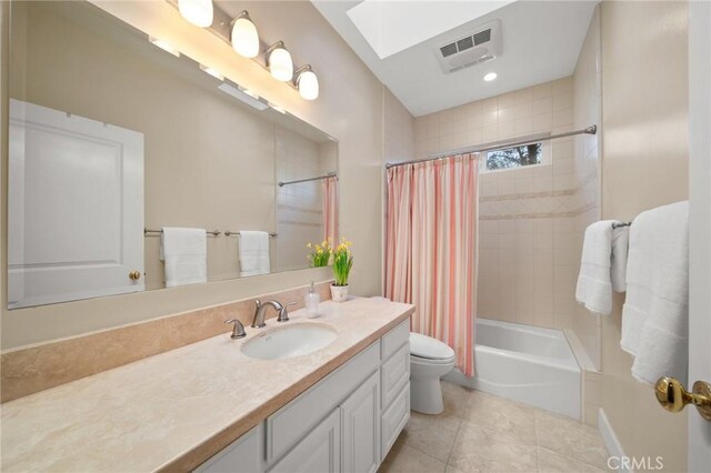 bathroom featuring vanity, toilet, tile patterned floors, a skylight, and visible vents