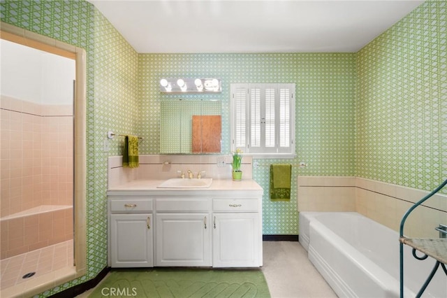 bathroom with vanity, a tile shower, a garden tub, and wallpapered walls