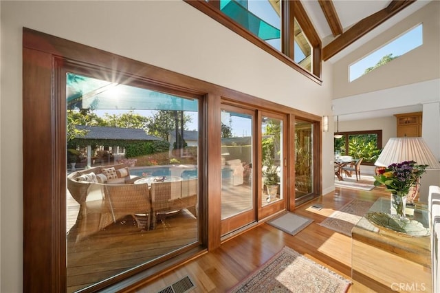 entryway with beamed ceiling, high vaulted ceiling, plenty of natural light, and wood finished floors