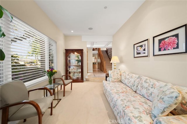 living room with stairs, a healthy amount of sunlight, and light carpet