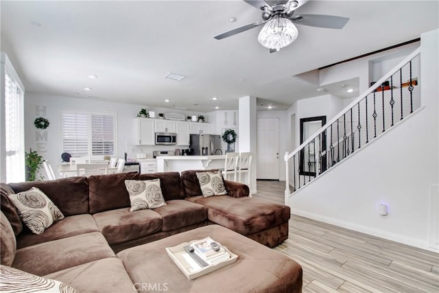 living room featuring light wood-style flooring, recessed lighting, baseboards, a ceiling fan, and stairway