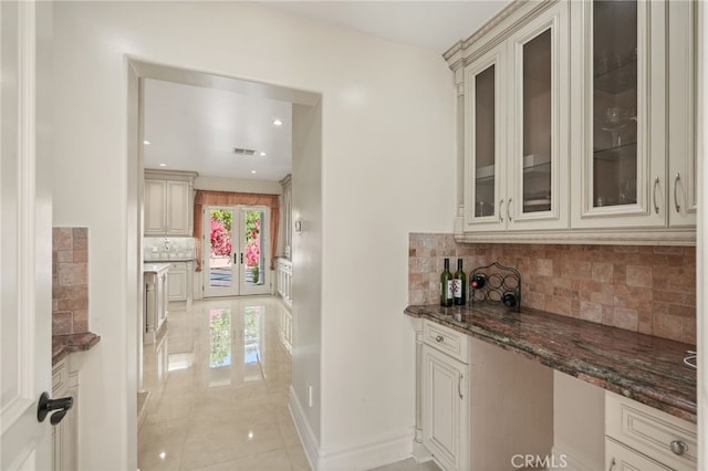 bar featuring french doors, backsplash, visible vents, light tile patterned floors, and baseboards