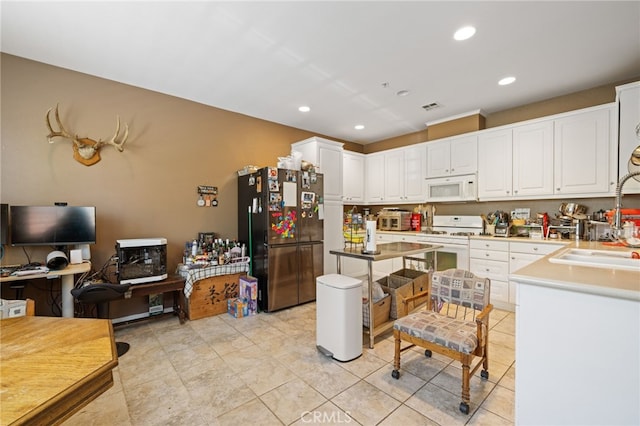 kitchen featuring visible vents, a sink, white cabinets, recessed lighting, and white appliances