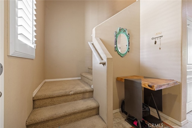 staircase featuring baseboards and carpet