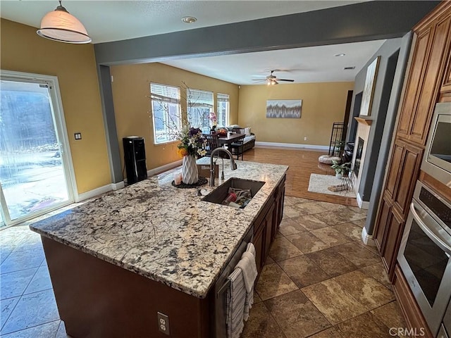 343 San Bernardino St, Los Banos, CA 93635 - kitchen featuring appliances with stainless steel finishes, a sink, baseboards, light stone countertops, and a fireplace with raised hearth